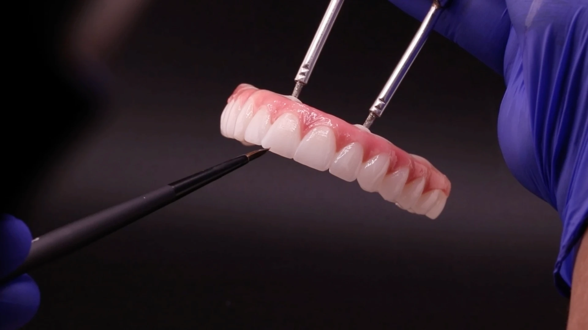 dental technician painting a final all-on-4 implant bridge